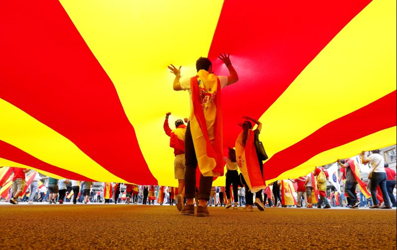 People walk under a huge Catalan flag during Spain's National Day in Barcelona
