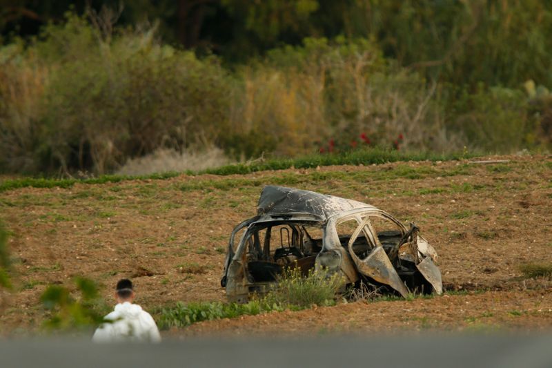 A forensics expert walks in a field after a powerful bomb blew up a car killing investigative journalist Daphne Caruana Galizia in Bidnija