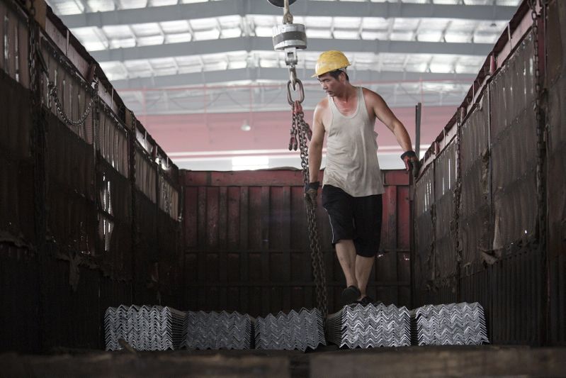 FILE PHOTO: A worker helps load steel bars onto a truck at warehouse of the Baifeng Iron and Steel Corporation in Tangshan in China's Hebei Province