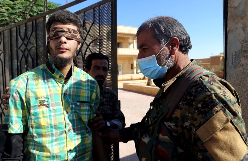 Members of Syrian Democratic Forces escort a blindfolded civilian detainee suspected to be a member of Islamic State militants in Raqqa