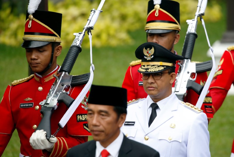 Presidential guards walk with Indonesia President Joko Widodo and Jakarta Governor Anies Baswedan for a swearing-in ceremony at the Presidential Palace in Jakarta