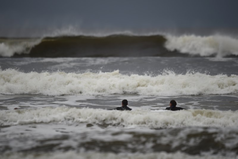 Surfers watch as waves approach in the Atlantic on the eve of storm Ophelia in an area where the tide should be out in the County Clare town of Lahinch