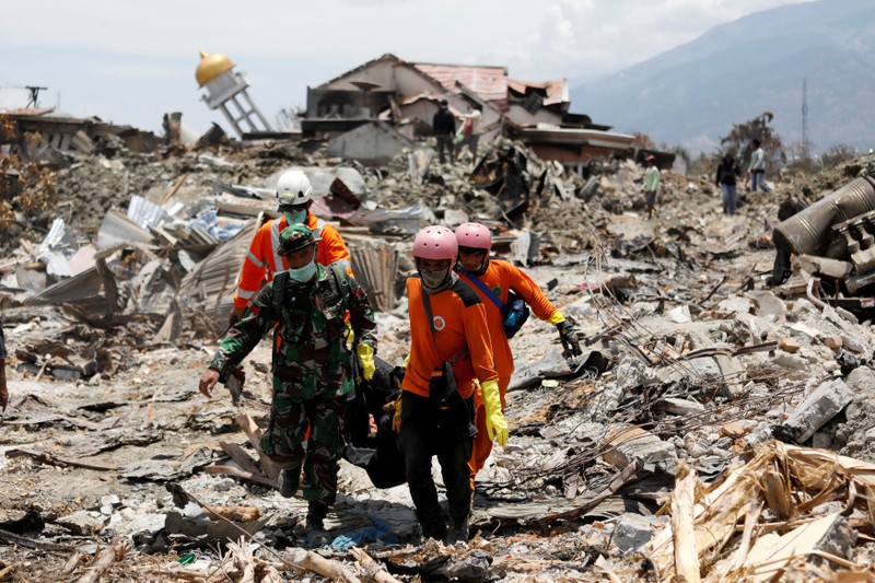 Rescue workers and a soldier remove a victim of last week's earthquake in the Balaroa neighbourhood in Palu, Central Sulawesi, Indonesia