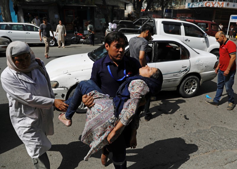 A man carries an injured woman to a hospital after a blast in Kabul, Afghanistan
