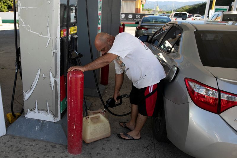 A man fills a container with fuel at a gas station after an earthquake in Guanica