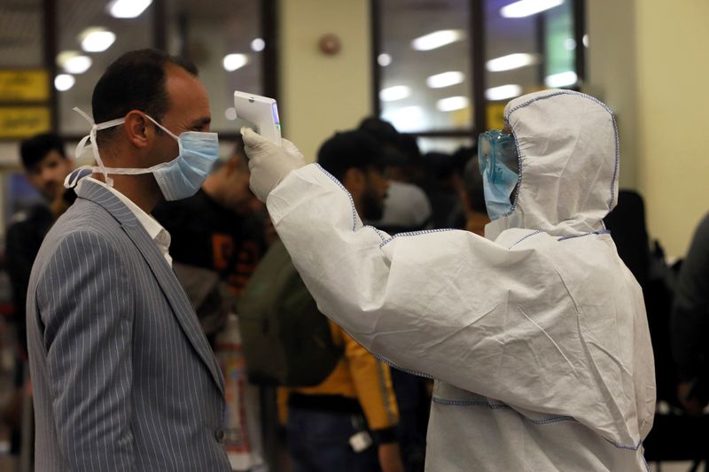 Passengers wearing masks, amid the new coronavirus outbreak, are checked by Iraqi Health Ministry employees upon their arrival at Basra airport, in Basra