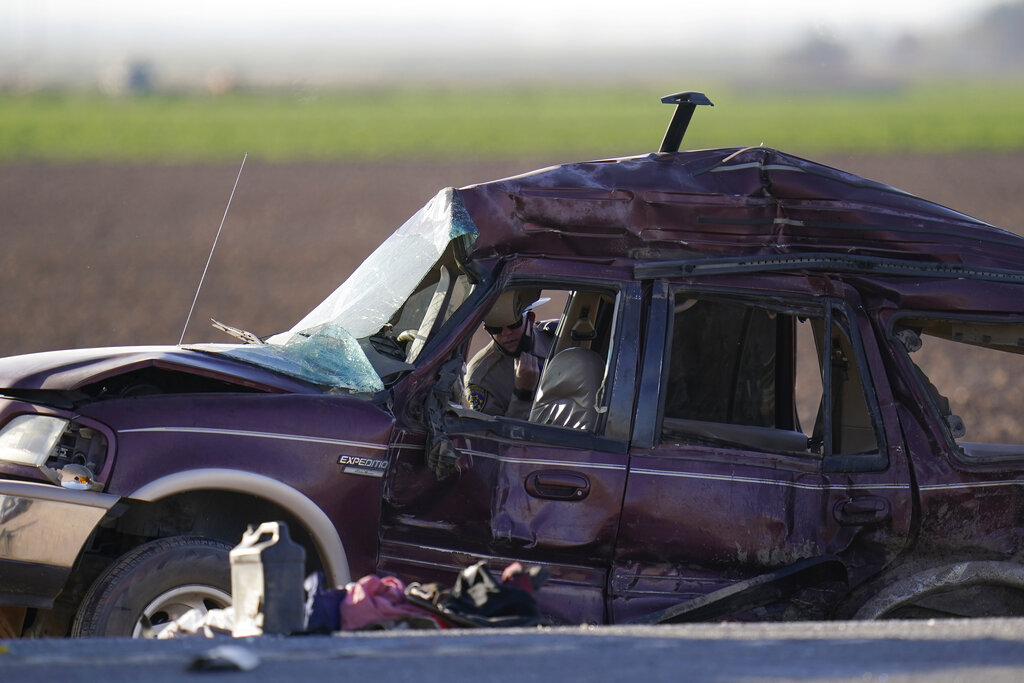 Law enforcement officers sort evidence and debris at the scene of a deadly crash in Holtville, Calif., on Tuesday, March 2, 2021. Authorities say a semi-truck crashed into an SUV carrying 25 people on a Southern California highway, killing at least 13 people. (AP Photo/Gregory Bull)