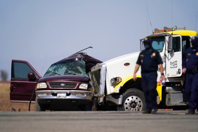 Law enforcement officers work at the scene of a deadly crash in Holtville, Calif., on Tuesday, March 2, 2021. Authorities say a semi-truck crashed into an SUV carrying 25 people on a Southern California highway, killing at least 13 people. (AP Photo/Gregory Bull)