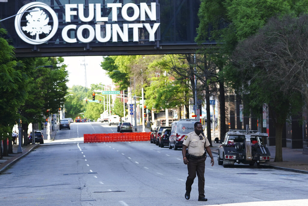 A Fulton County Sheriff's deputy walks on a closed street outside the Fulton County Courthouse ahead of the seating of a special grand jury in the investigation into whether former President Donald Trump and others illegally tried to influence the 2020 election in Georgia, Monday, May 2, 2022, in Atlanta. (AP Photo/John Bazemore)