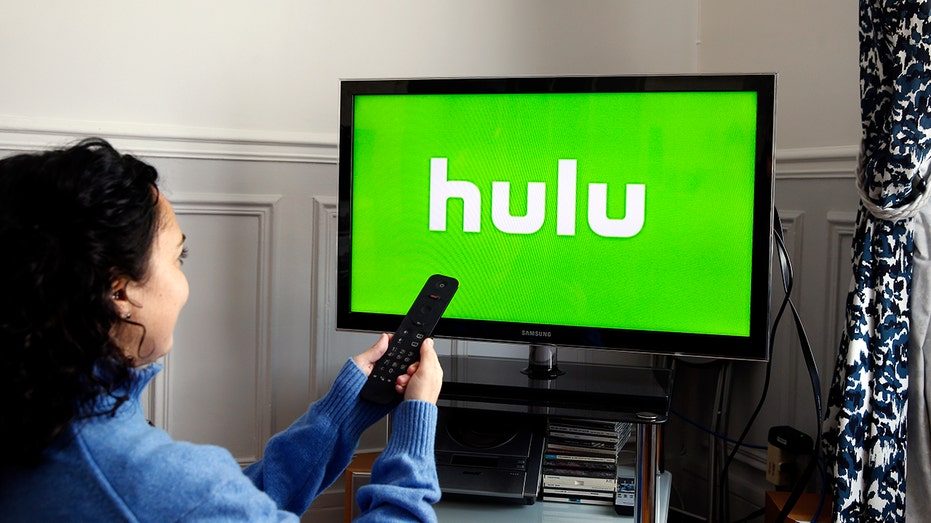 Hulu logo on screen in front of woman wearing blue sweater