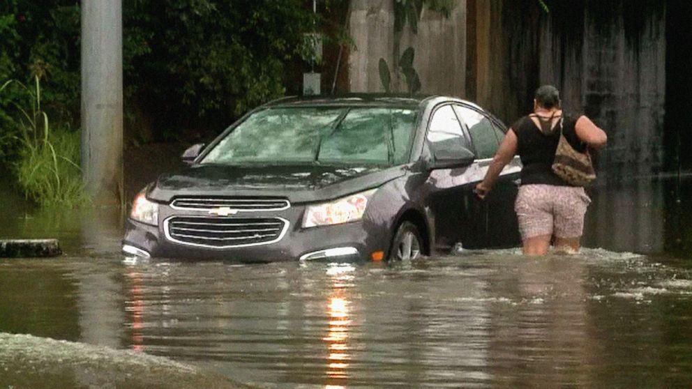 PHOTO: A woman walks to her car, which was flooded during rain deluge in Jackson, Miss., Aug. 23, 2022. 