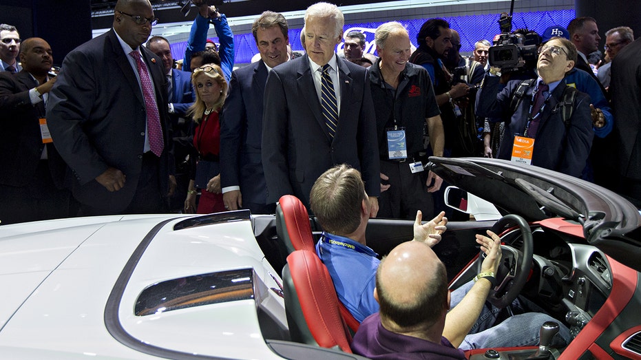 Biden looking on as a person sits in a convertible