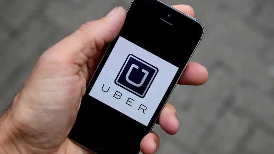 A person holding a smartphone with an Uber app logo