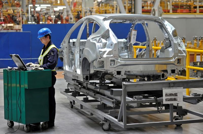 An employee uses a laptop next to a car body at an assembly line at a Ford manufacturing plant in Chongqing