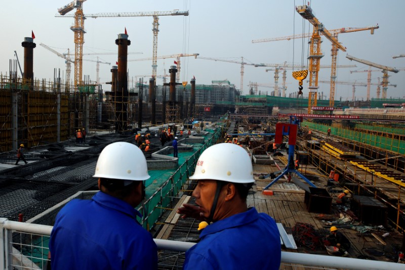 FILE PHOTO: Workers survey the construction site of the terminal for the Beijing New Airport in Beijing