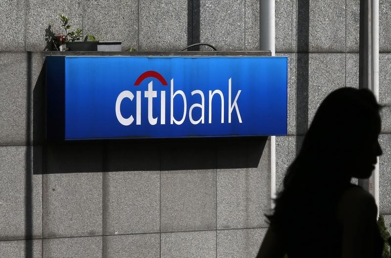 A woman walks past a Citibank logo displayed outside the Citibank Plaza in Hong Kong