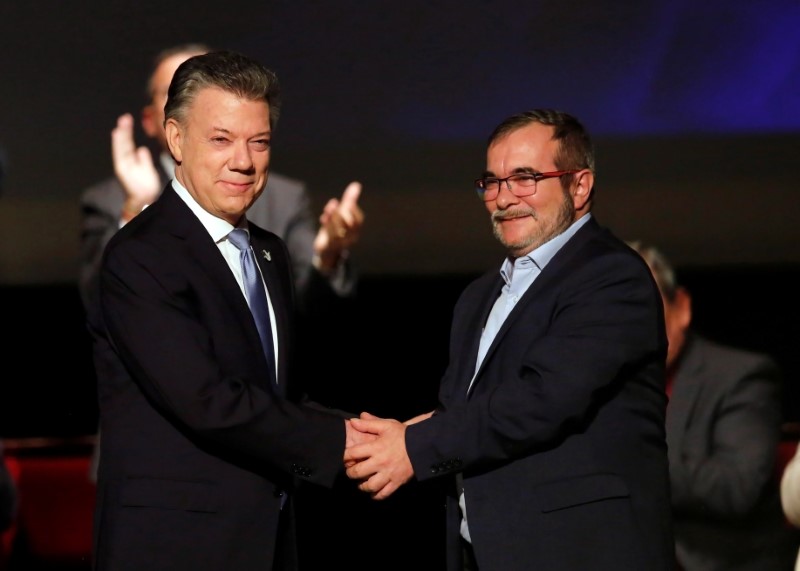 Colombia's President Juan Manuel Santos and Marxist FARC rebel leader Rodrigo Londono known as Timochenko shake hands after signing a peace accord in Bogota