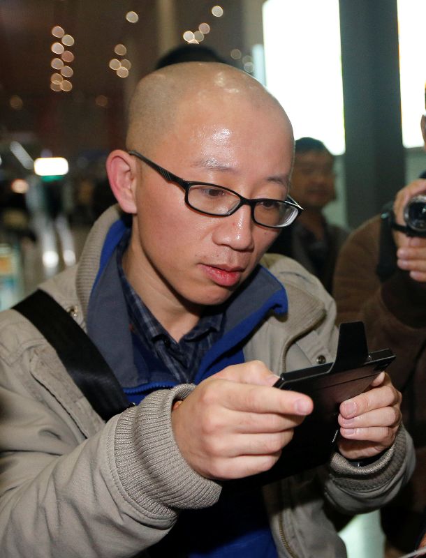 FILE PHOTO - Chinese dissident Hu Jia uses his mobile phone at Beijing airport