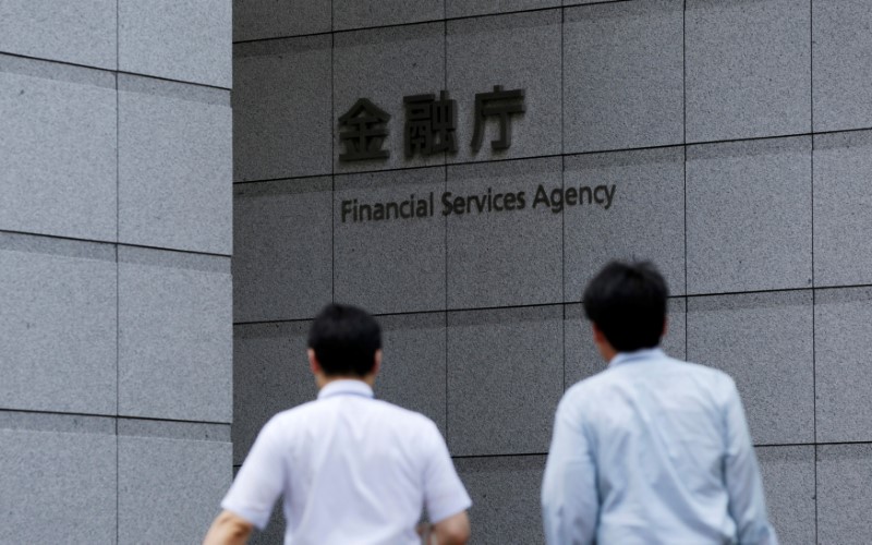 FILE PHOTO: Men walk toward a sign of Japan's Financial Services Agency in Tokyo