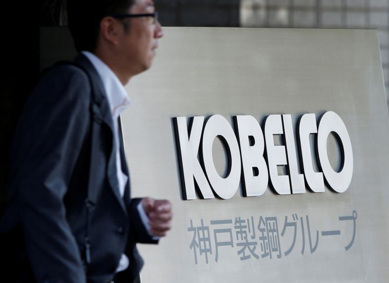FILE PHOTO: A man walks past the signboard of Kobe Steel at the group's Tokyo headquarters in Tokyo