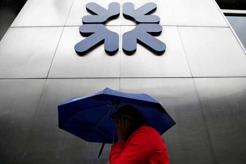 FILE PHOTO: A woman shelters under an umbrella as she walks past a branch of RBS in the City of London