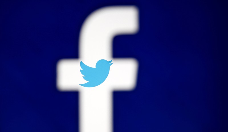 A 3D-printed Facebook logo is displayed in front of the Twitter logo, in this illustration