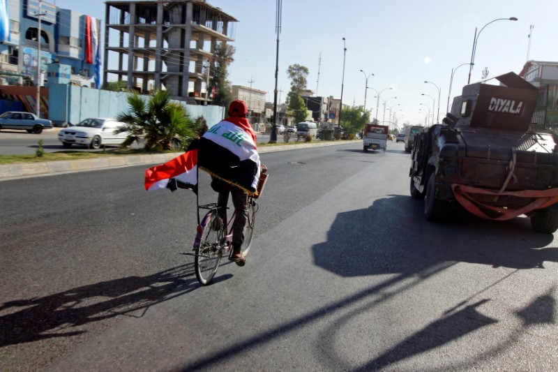 A man rides a bicycle with Iraqi flag in north of Kirkuk