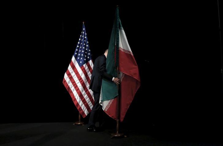 FILE PHOTO - A staff member removes the Iranian flag from the stage after a group picture with foreign ministers and representatives during the Iran nuclear talks at the Vienna International Center in Vienna