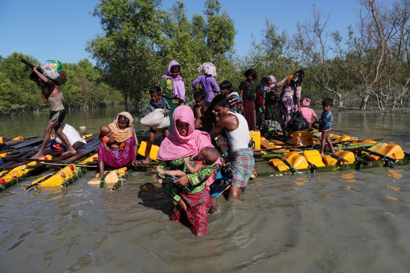 Rohingya refugees come out of an improvised raft after crossing the Naf River at Sabrang near Teknaf