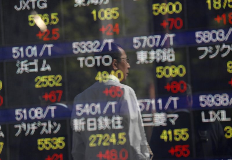 Passersby are reflected in an electronic stock quotation board outside a brokerage in Tokyo