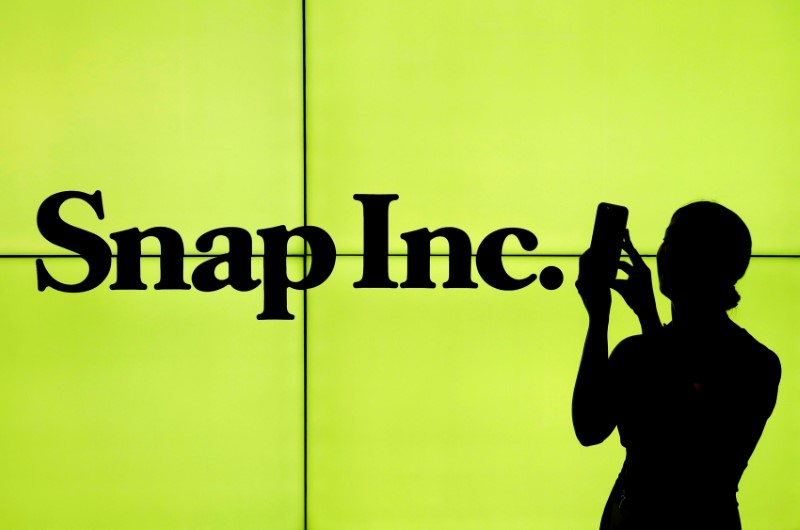 FILE PHOTO - A woman stands in front of the logo of Snap Inc. on the floor of the New York Stock Exchange in New York City