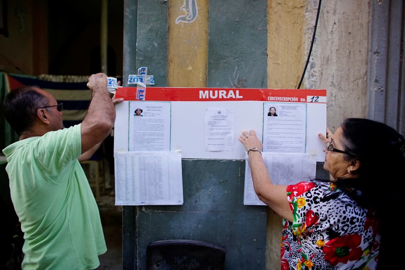 Election officials hang pictures and CVs of municipal assembly candidates in Havana