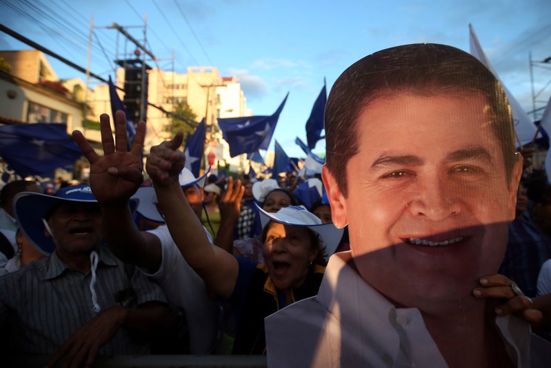 A supporter of President and National Party presidential candidate Juan Orlando Hernandez holds an image of Hernandez as she waits for official presidential election results in Tegucigalpa
