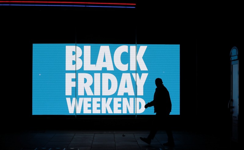 A man is silhouetted against an illuminated sign on 'Black Friday' in the West End shopping district of London