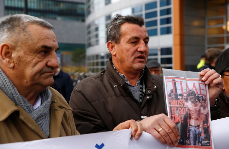 Fikret Alic, one of the survivors of concentration camps shows his photo on the cover of Time before the trial of former Bosnian Serb military commander Ratko Mladic before a court at the International Criminal Tribunal for the former Yugoslavia (ICTY) in