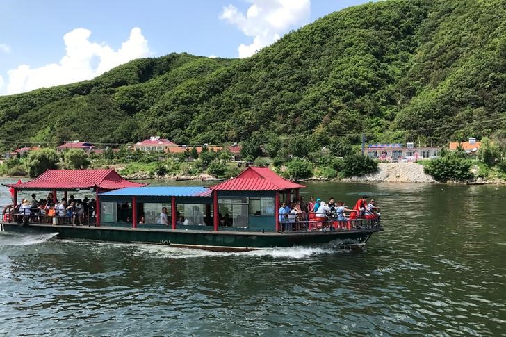 Chinese tourists are seen a boat taking them from the Chinese side of the Yalu River for sightseeing close to the shores of North Korea, near Dandong