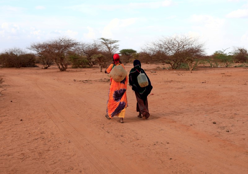 Internally displaced women from drought hit area, carry their jerry cans filled with water as they walk toward their shelter at a makeshift settlement in Dollow, Somalia