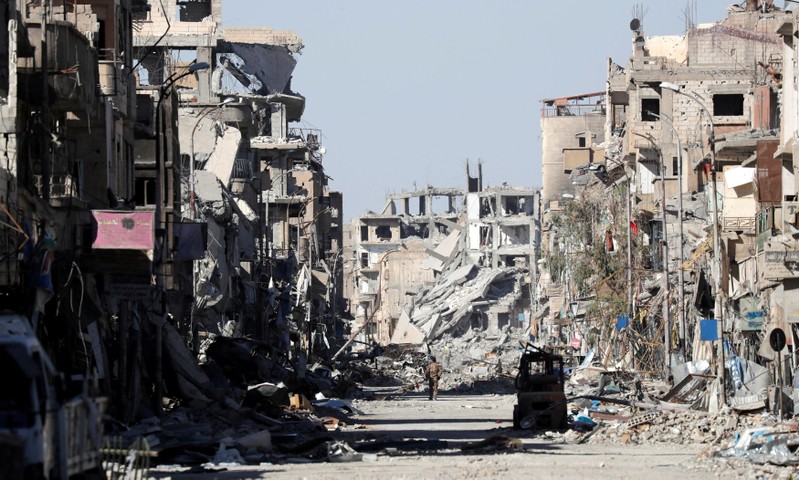 FILE PHOTO: A fighter of Syrian Democratic Forces stands amidst the ruins of buildings near the Clock Square in Raqqa