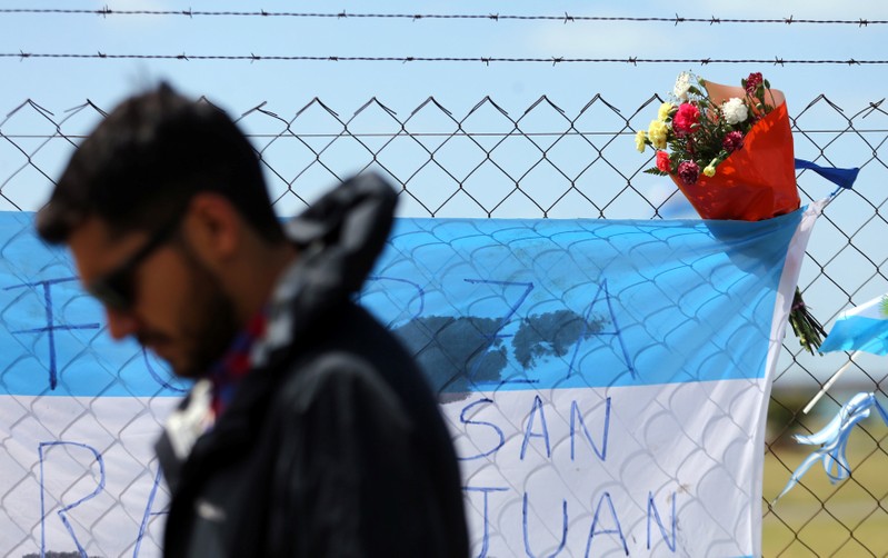 A friend of Tagliapietra, one of the 44 crew members of the missing at sea ARA San Juan submarine, walks by a bouquet of flowers placed on a fence at an Argentine naval base in Mar del Plata