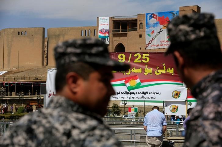 Kurdish policemen look on towards banners supporting the referendum for independence of Kurdistan in Erbil