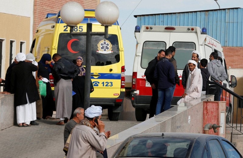 Relatives of victims of the explosion at Al Rawdah mosque, wait near past ambulances, in Ismailia