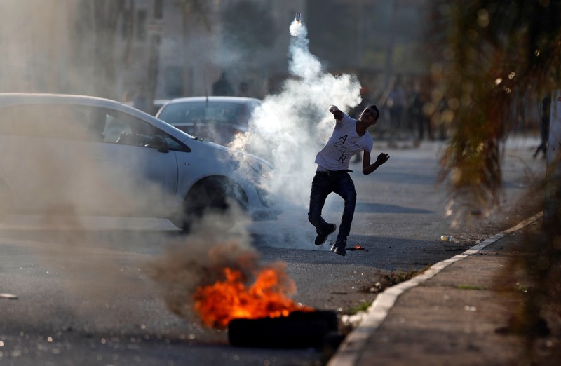 A Palestinian protester hurls back a tear gas canister fired by Israeli troops during clashes in the West Bank village of Qusrah near Nablus