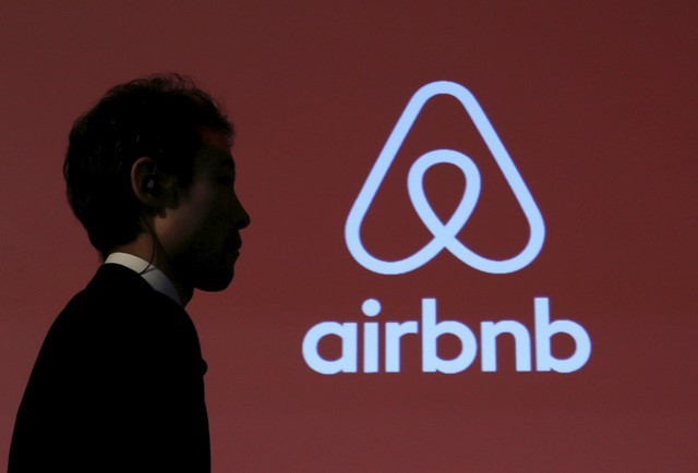 FILE PHOTO: A man walks past a logo of Airbnb after a news conference in Tokyo