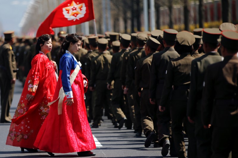 Women wearing traditional clothes walk past North Korean soldiers after an opening ceremony for a newly constructed residential complex in Ryomyong street in Pyongyang