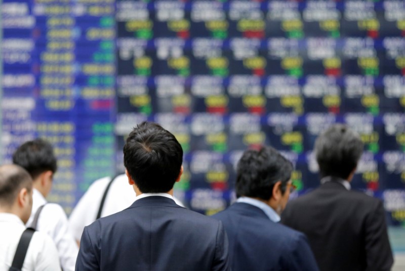 People walk past an electronic stock quotation board outside a brokerage in Tokyo