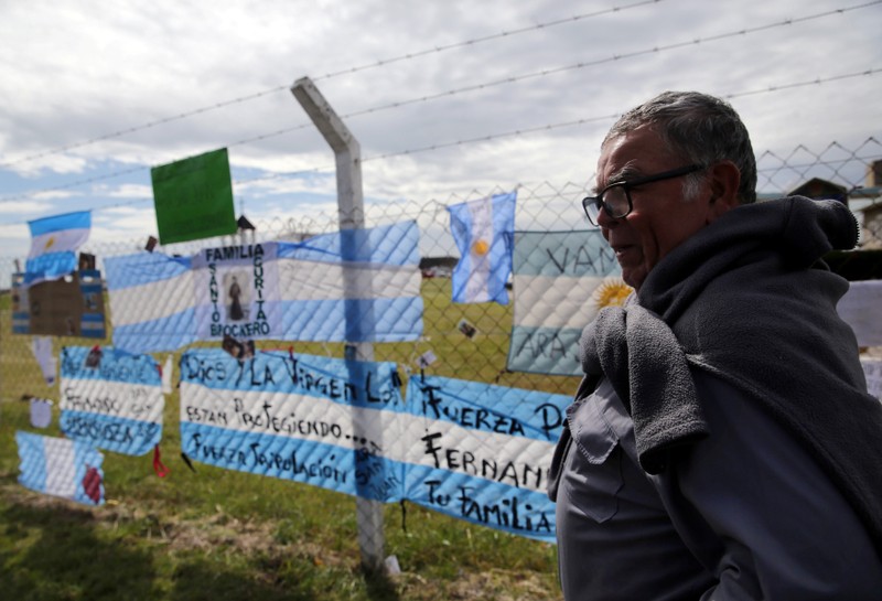 The father of Coronel, one of the 44 crew members of the missing at sea ARA San Juan submarine, stands next to signs in support of the crew outside an Argentine naval base in Mar del Plata