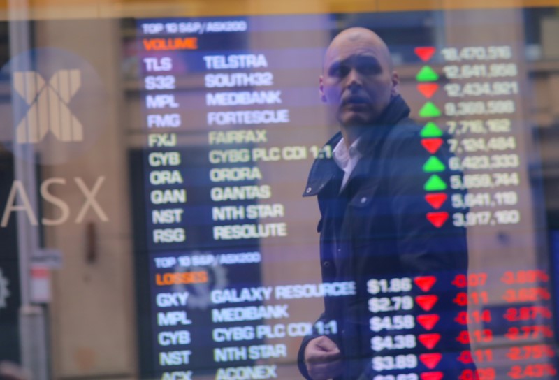An investor is reflected in a window displaying a board showing stock prices at the Australian Securities Exchange in Sydney