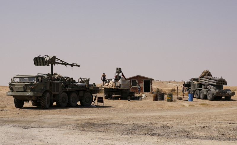 A man stands near military vehicles that belong to the Syrian army in Deir al-Zor