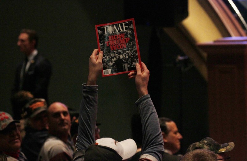 A supporter holds up a copy of Time Magazine with the cover headline 