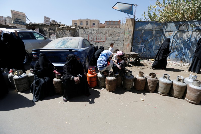 Women sit on cooking gas cylinders lined up outside a gas station amid supply shortage in Sanaa